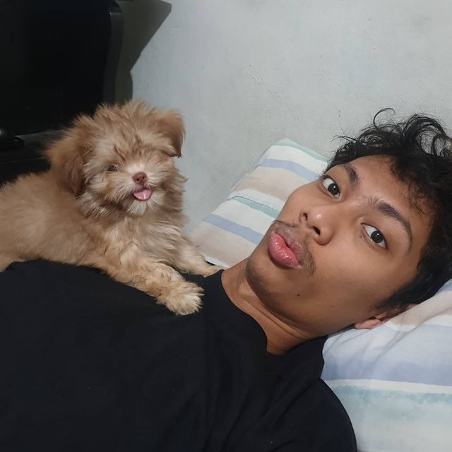 Emman Nimedez in a black t-shirt posing with his pet.